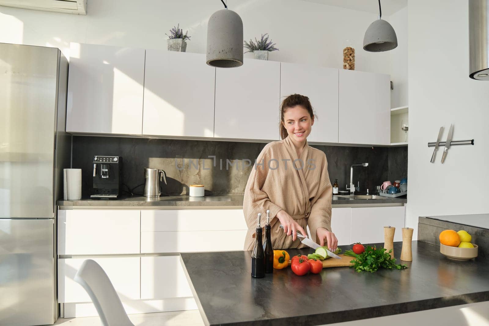 Portrait of good-looking woman cooking salad in the kitchen, chopping vegetables and smiling, preparing healthy meal, leading healthy lifestyle and eating raw food.