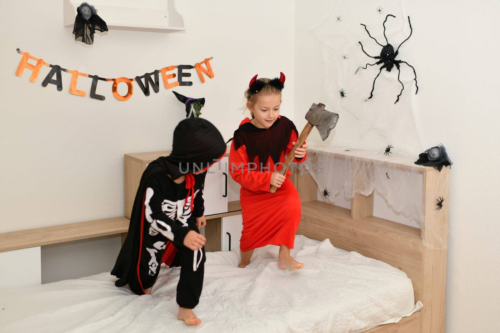 Children in skeleton and witch costume laughing at home halloween