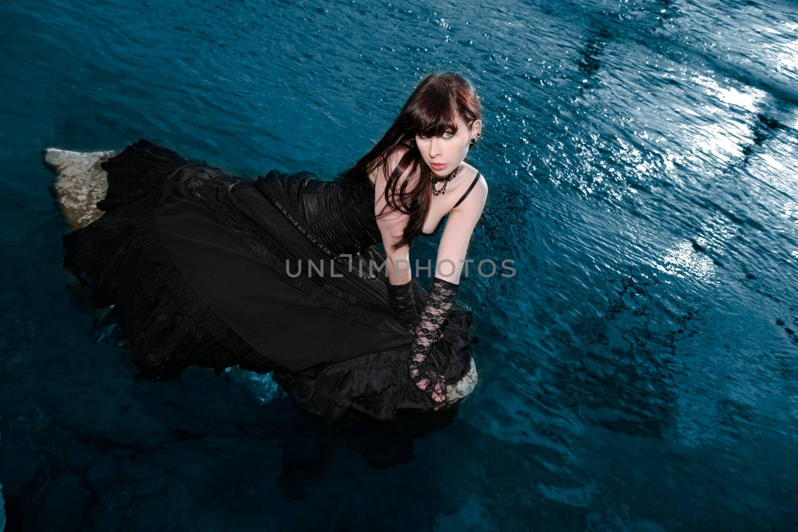young woman on a stone in the water