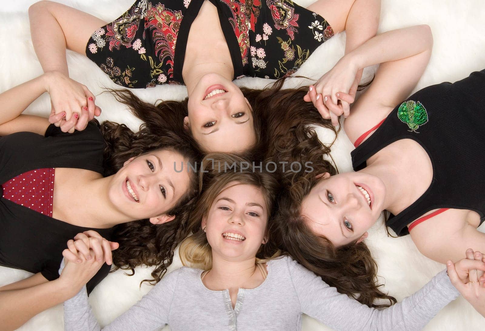4 teen girls laying on white background