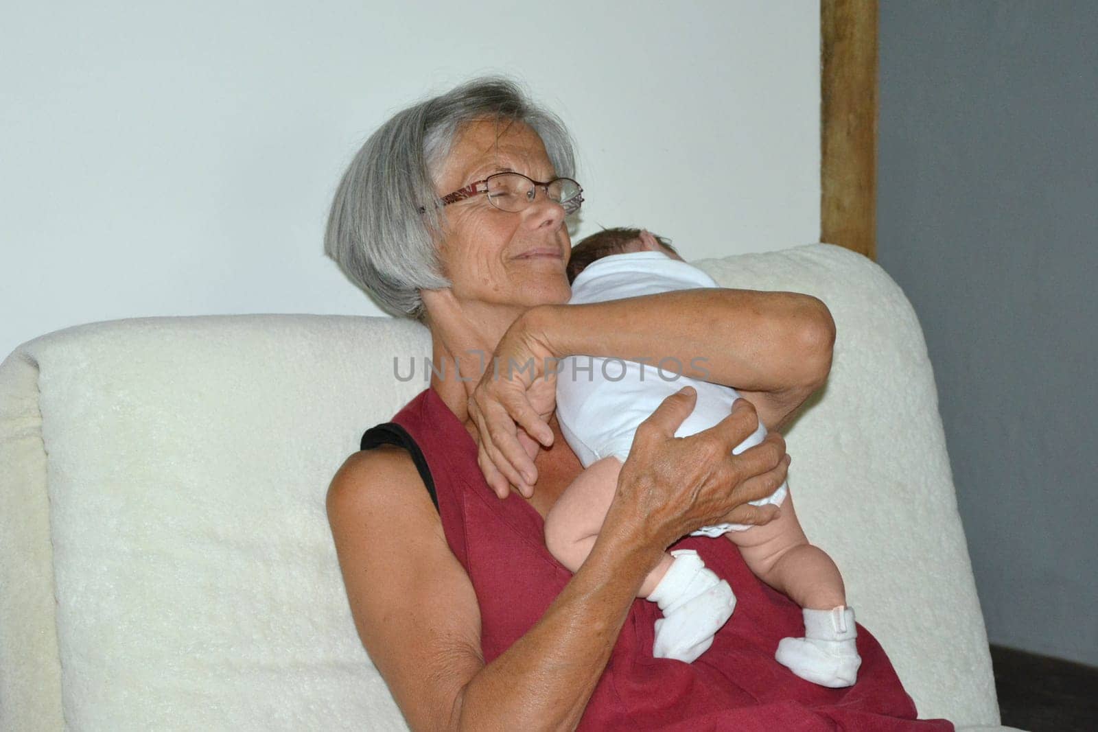 A grey-haired grandmother holding a newborn baby