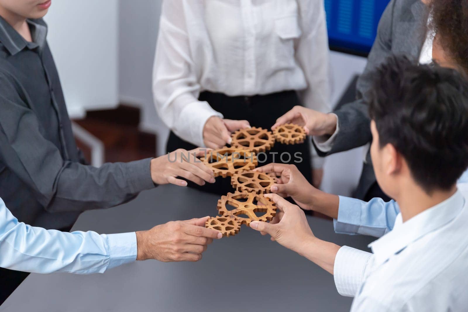 Office worker holding cog wheel as unity and teamwork in corporate workplace concept. Diverse colleague business people showing symbol of visionary system and mechanism for business success. Concord