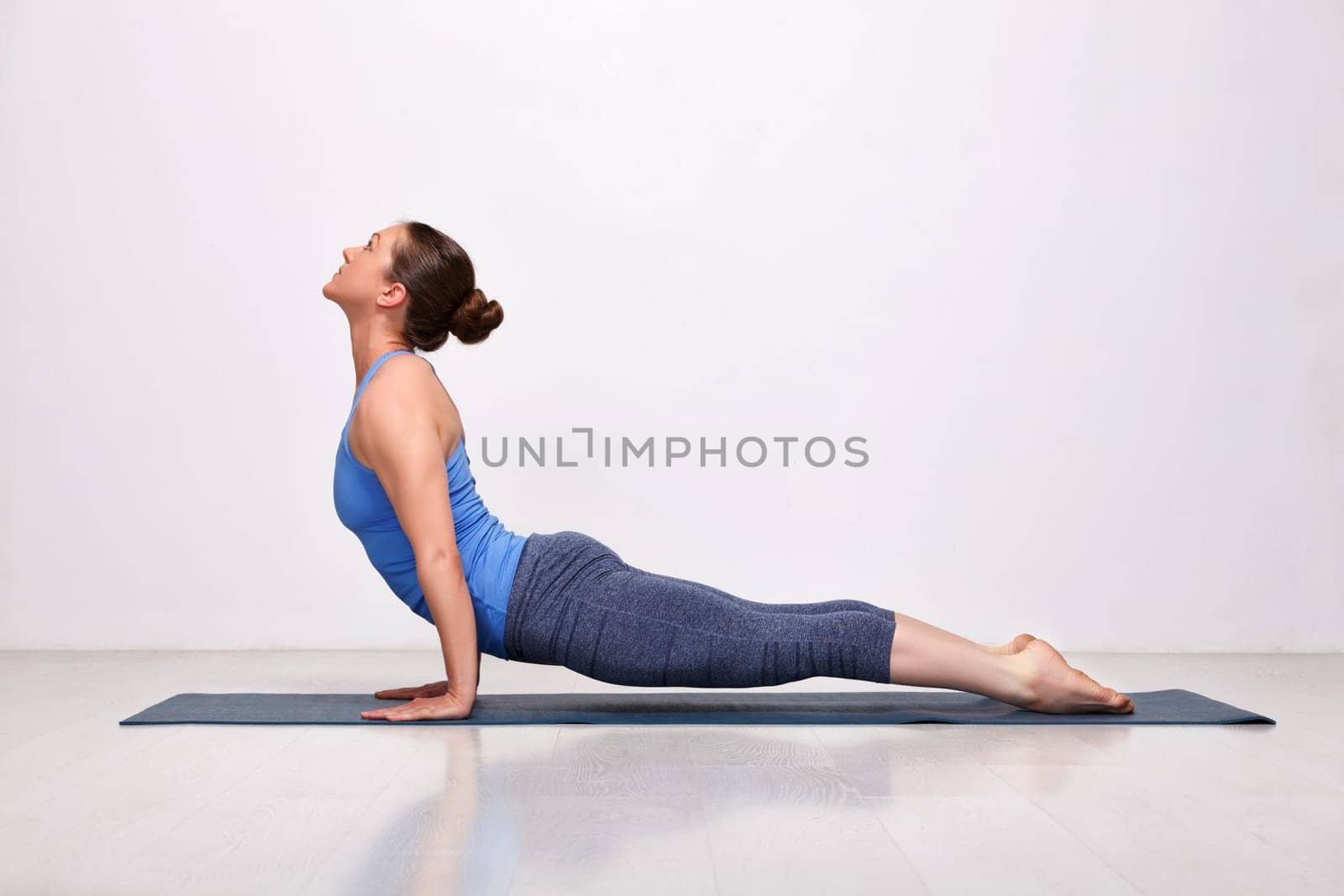 Beautiful sporty fit yogini woman practices yoga asana urdhva mukha svanasana - upward facing dog pose in studio