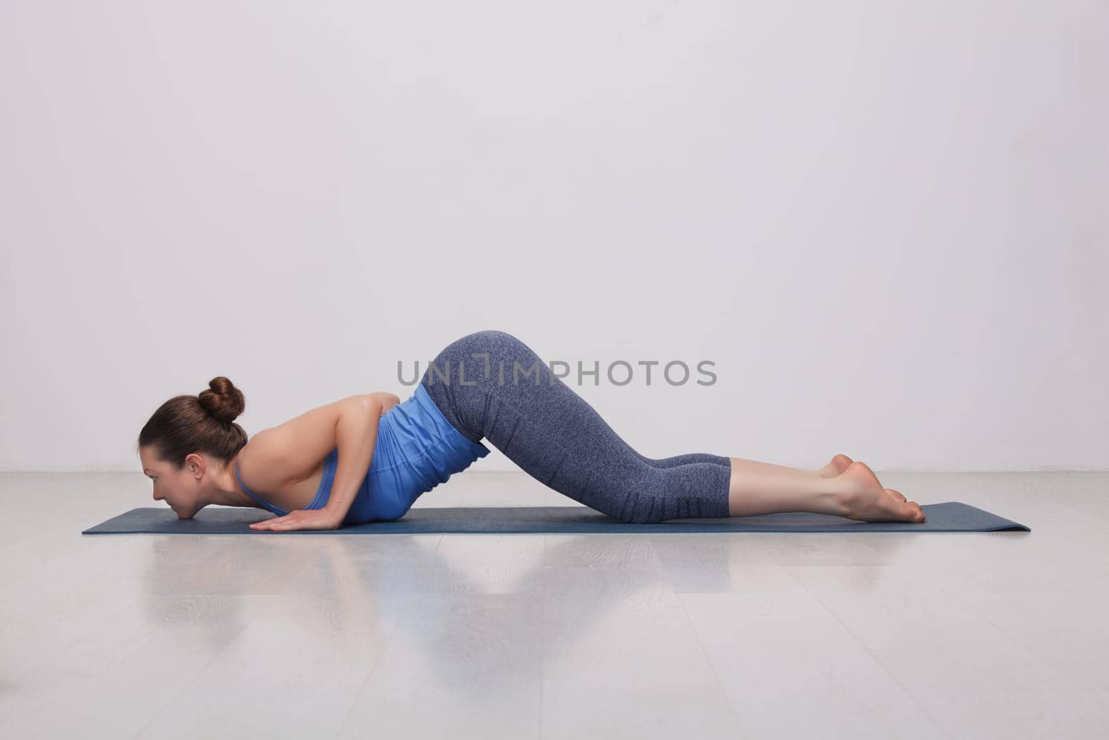 Sporty fit yogini woman practices yoga asana Ashtangasana by dimol