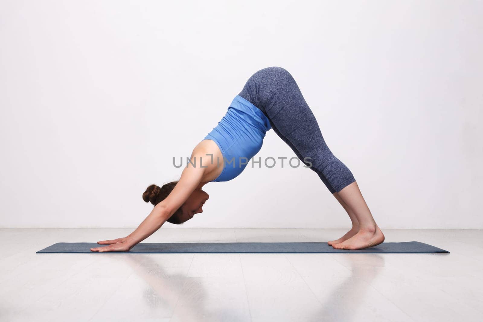 Beautiful sporty fit yogi girl practices yoga asana adhomukha sv by dimol