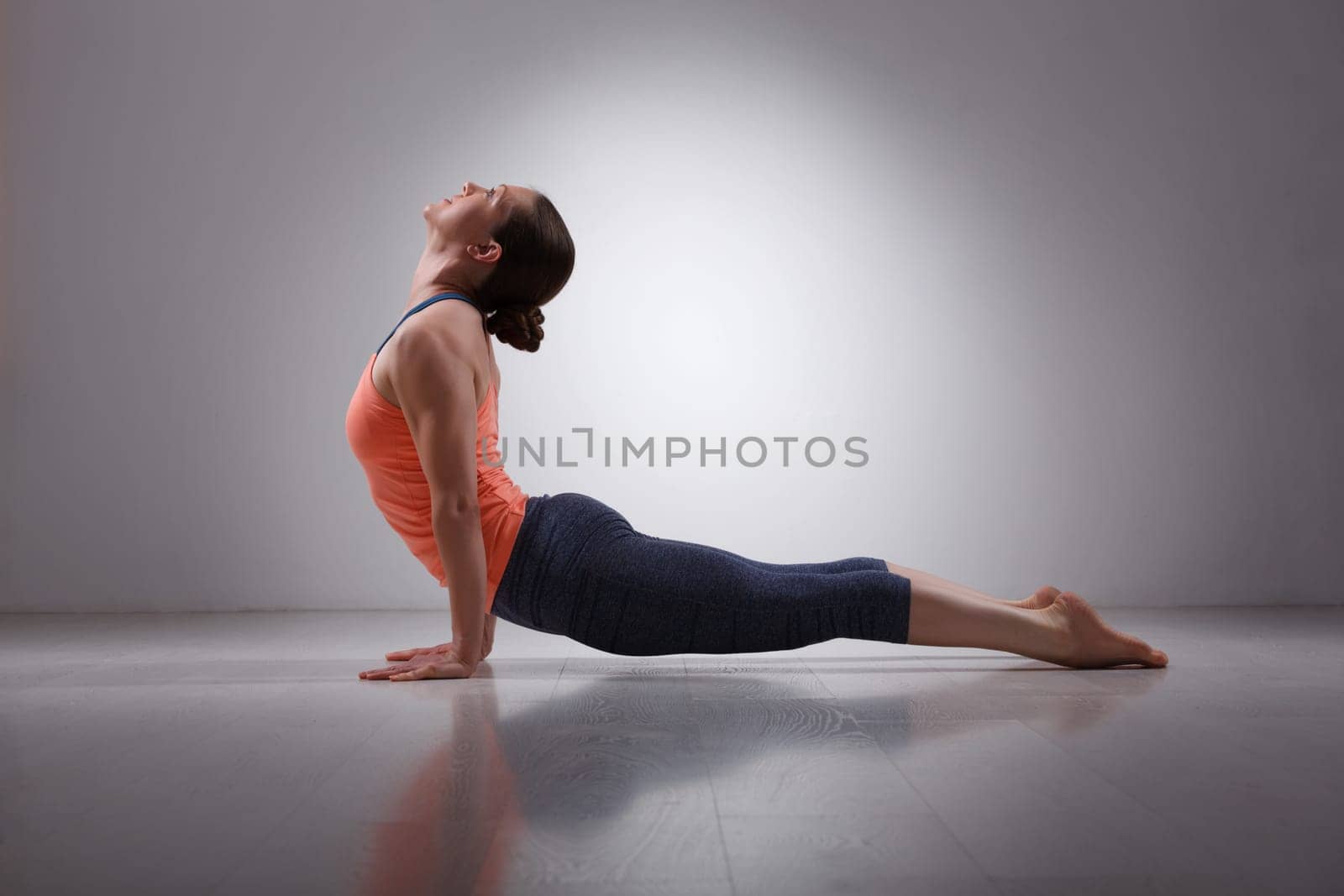 Beautiful sporty fit yogini woman practices yoga asana urdhva mukha svanasana - upward facing dog pose in studio