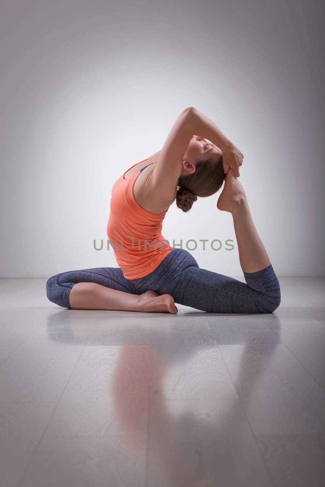 Beautiful sporty fit yogini woman practices yoga asana Eka pada rajakapotasana - one-legged king pigeon pose in studio