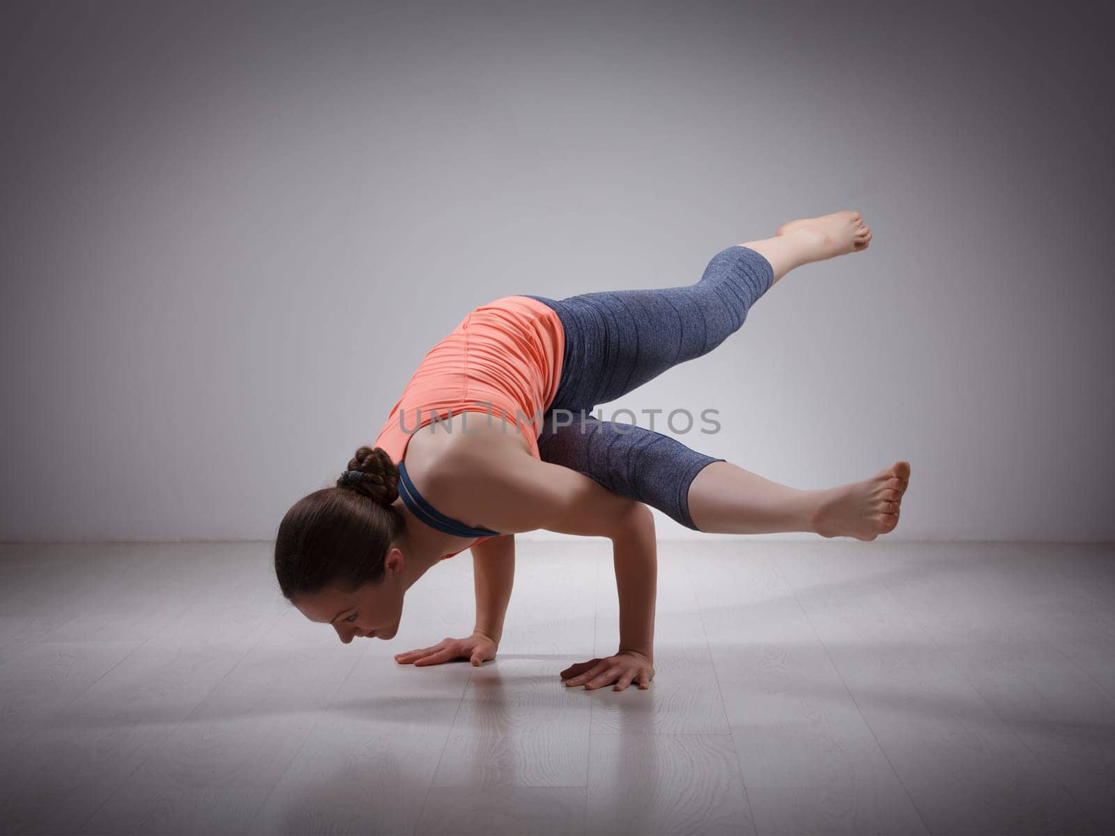 Beautiful sporty fit yogini woman practices yoga asana eka pada koundinyasana 1 - pose 1 dedicated to sage Koundinya pose in studio