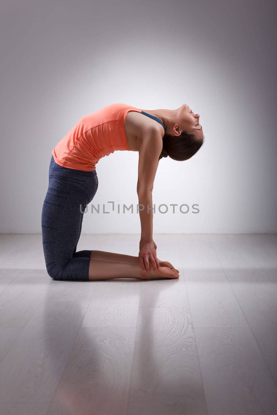 Beautiful sporty fit yogini woman practices yoga asana ustrasana - camel pose in studio