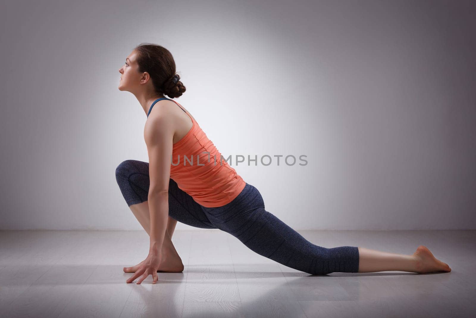 Fit yogini woman practices yoga asana Anjaneyasana by dimol