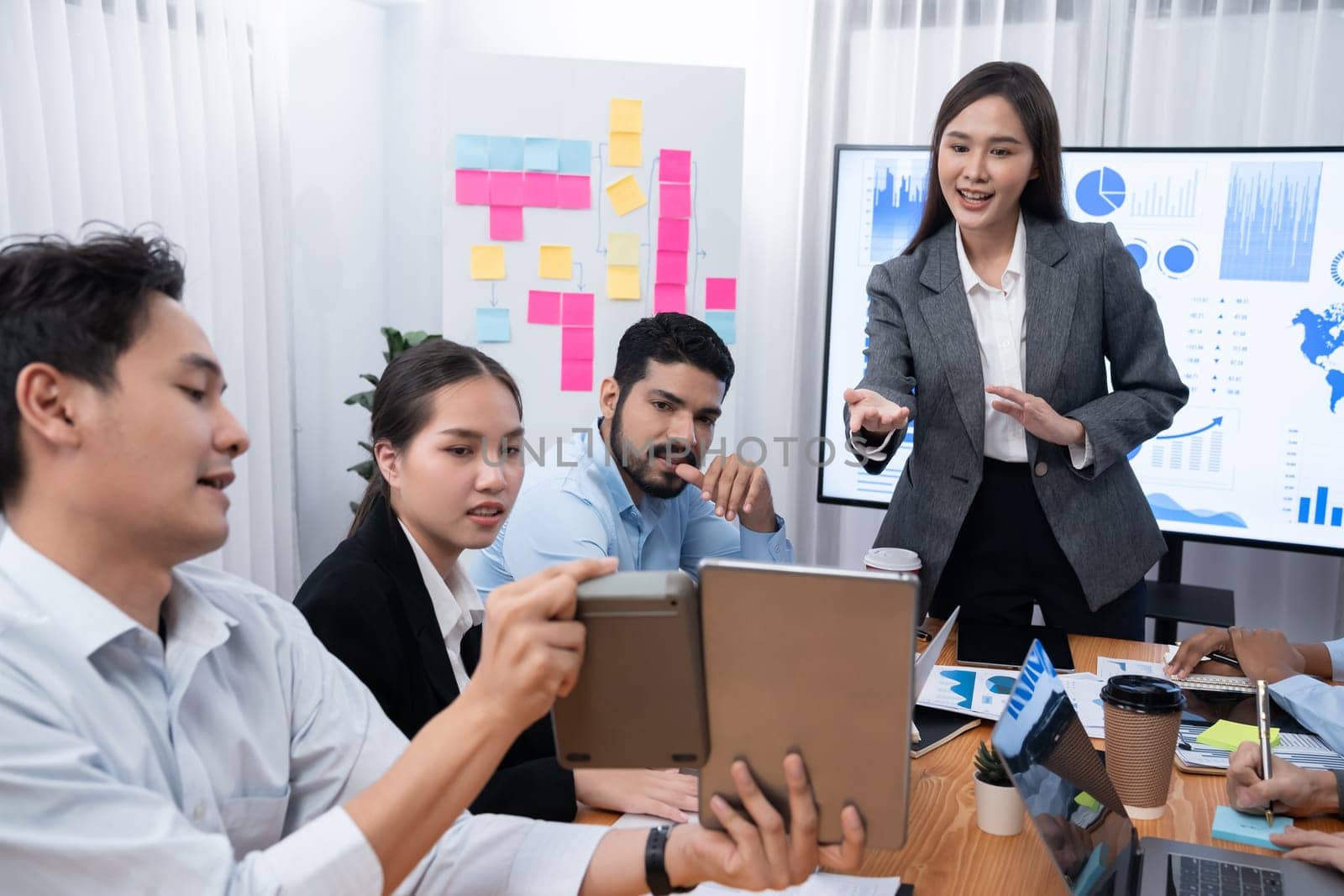 Young asian businesswoman presenting data analysis dashboard on TV screen in modern meeting. Business presentation with group of business people in conference room. Concord