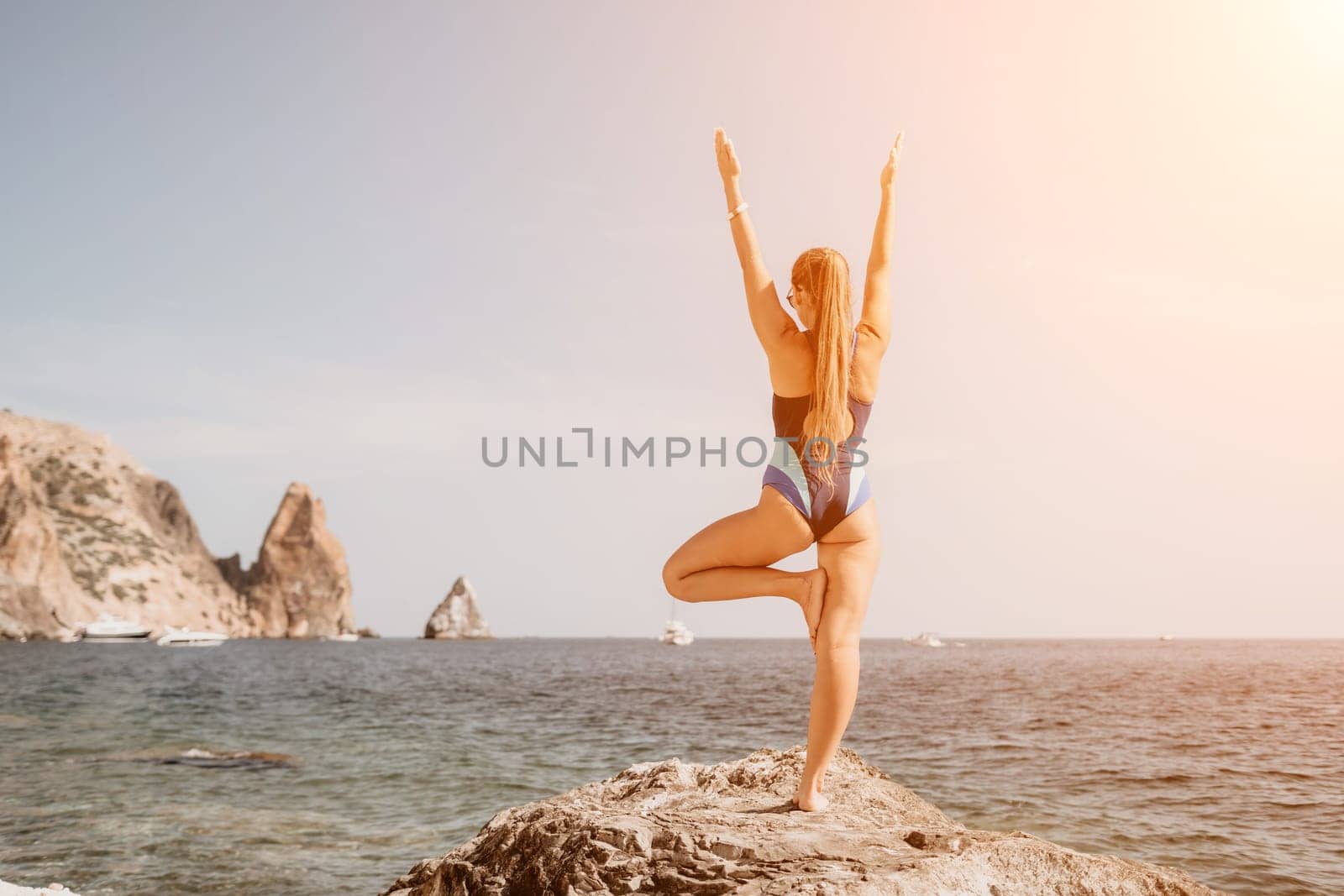 Woman sea yoga. Happy woman meditating in yoga pose on the beach, ocean and rock mountains. Motivation and inspirational fit and exercising. Healthy lifestyle outdoors in nature, fitness concept. by panophotograph