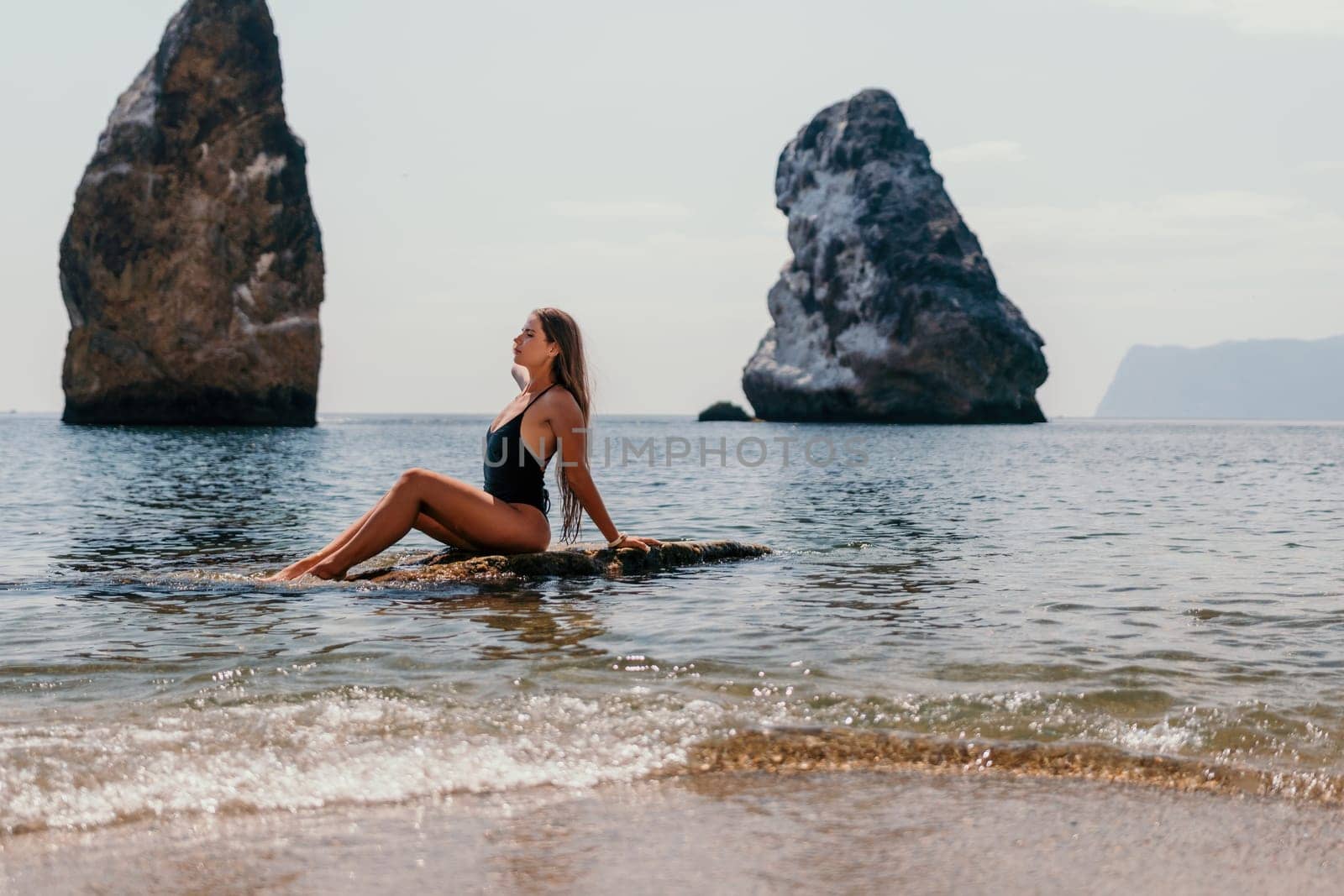 Woman summer travel sea. Happy tourist enjoy taking picture outdoors for memories. Woman traveler posing on the beach at sea surrounded by volcanic mountains, sharing travel adventure journey by panophotograph