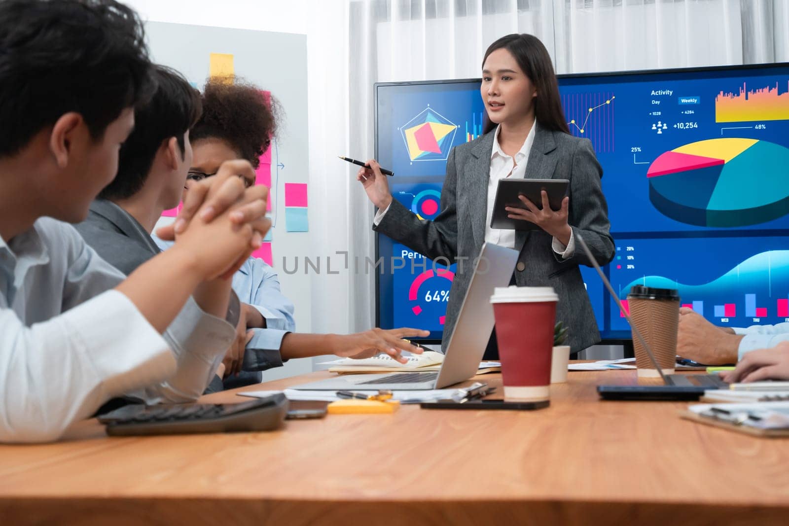 Young asian businesswoman presenting data analysis dashboard on TV screen in modern meeting. Business presentation with group of business people in conference room. Concord