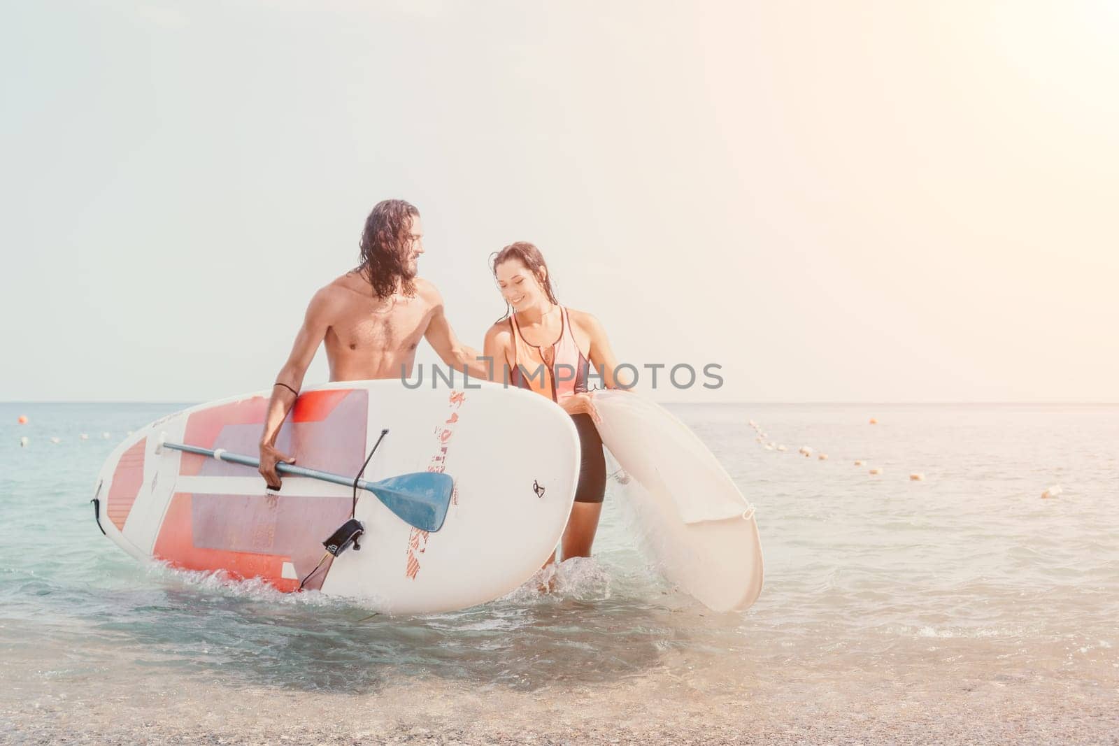 Woman man sea sup. Close up portrait of beautiful young caucasian woman with black hair and freckles looking at camera and smiling. Cute woman portrait in a pink bikini posing on sup board in the sea by panophotograph