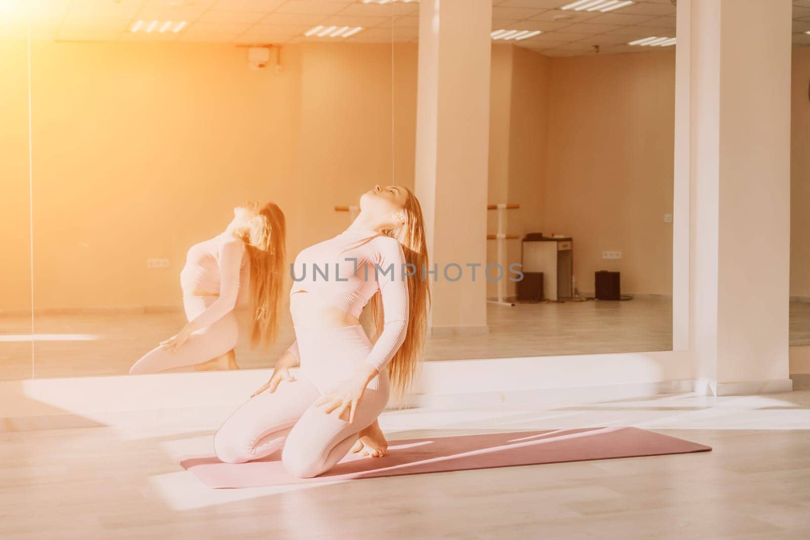 Young woman with long hair in white swimsuit and boho style braclets practicing outdoors on yoga mat by the sea on a sunset. Women's yoga fitness routine. Healthy lifestyle, harmony and meditation