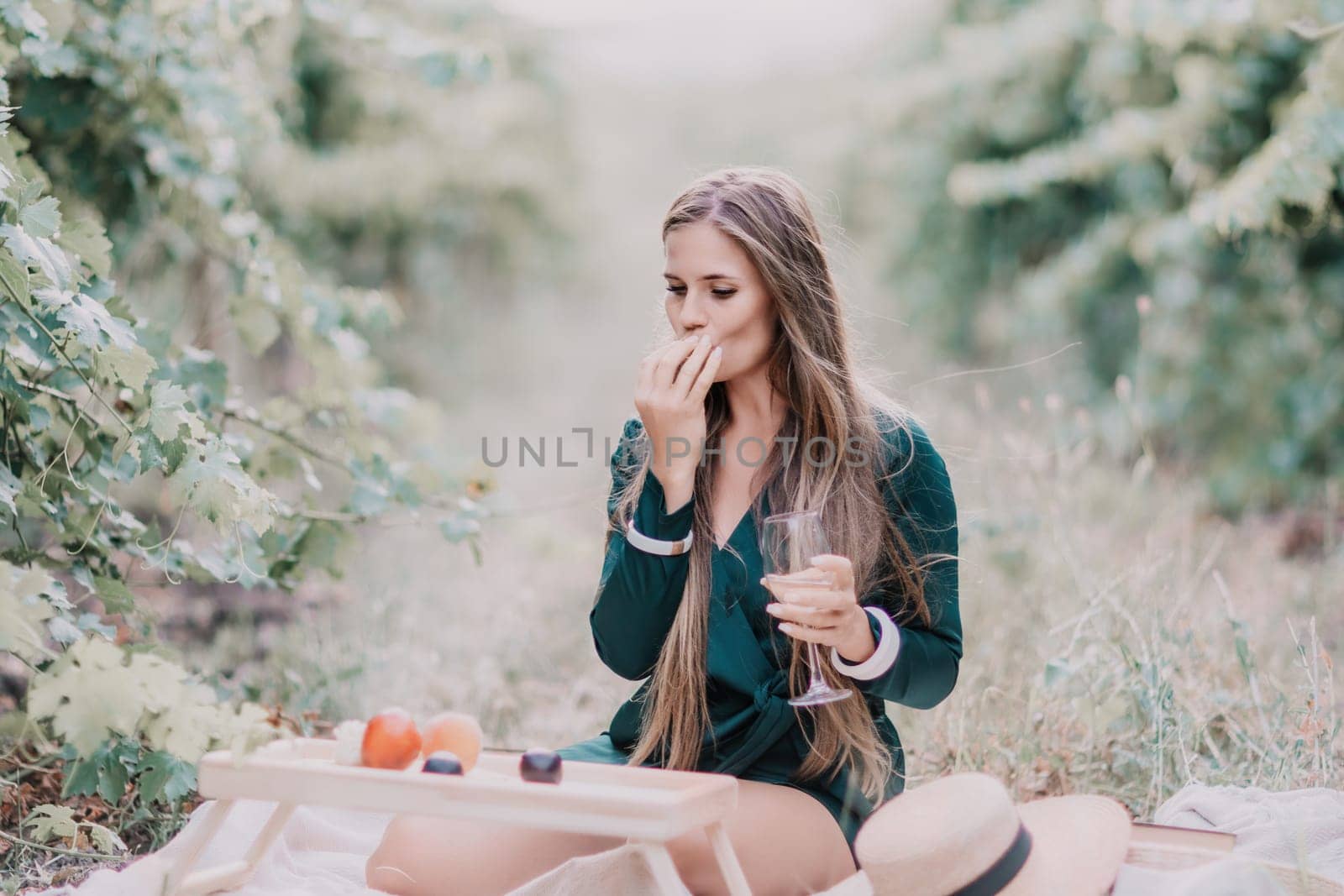 Woman picnic vineyard. Happy woman with a glass of wine at a picnic in the vineyard, wine tasting at sunset and open nature in the summer. Romantic dinner, fruit and wine. by panophotograph