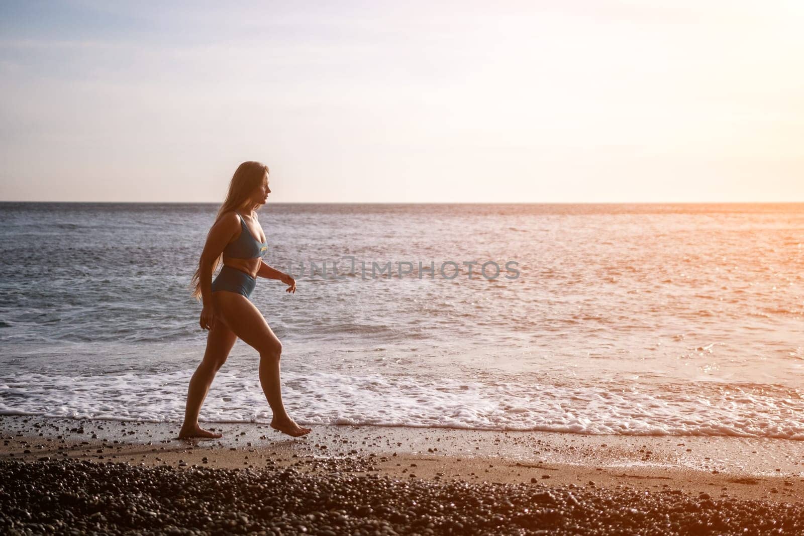 Running woman on a summer beach. A woman jogging on the beach at sunrise, with the soft light of the morning sun illuminating the sand and sea, evoking a sense of renewal, energy and health. by panophotograph