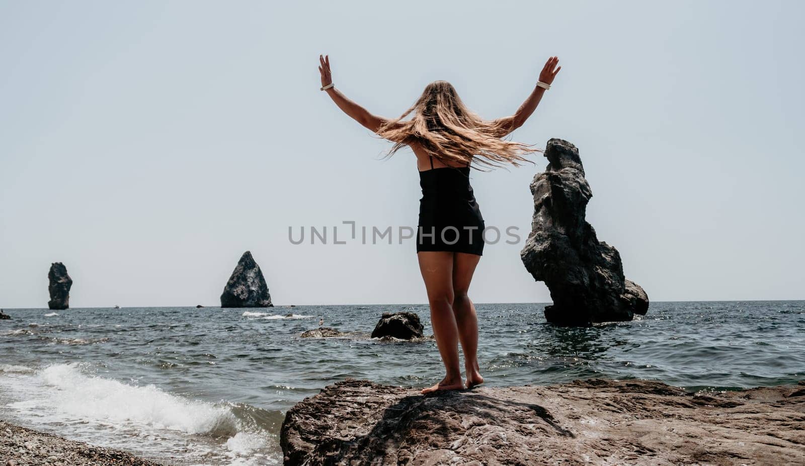 Woman summer travel sea. Happy tourist in hat enjoy taking picture outdoors for memories. Woman traveler posing on the beach at sea surrounded by volcanic mountains, sharing travel adventure journey by panophotograph