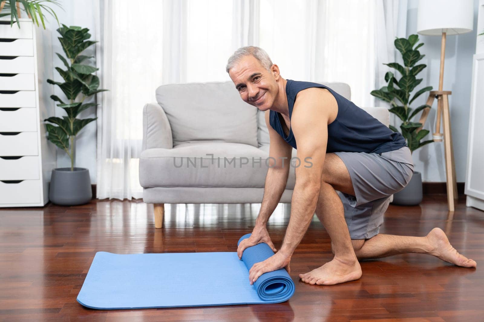 Active and sporty senior man preparing fitness mat. Clout by biancoblue