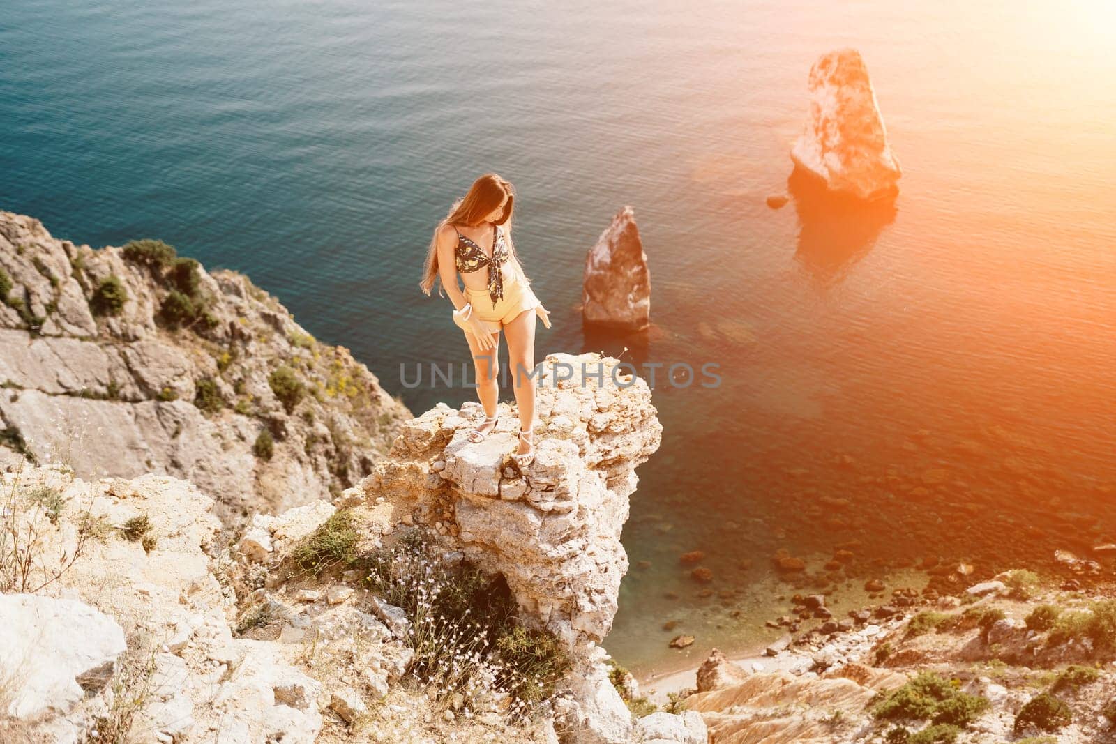 Woman travel sea. Happy tourist taking picture outdoors for memories. Woman traveler looks at the edge of the cliff on the sea bay of mountains, sharing travel adventure journey.