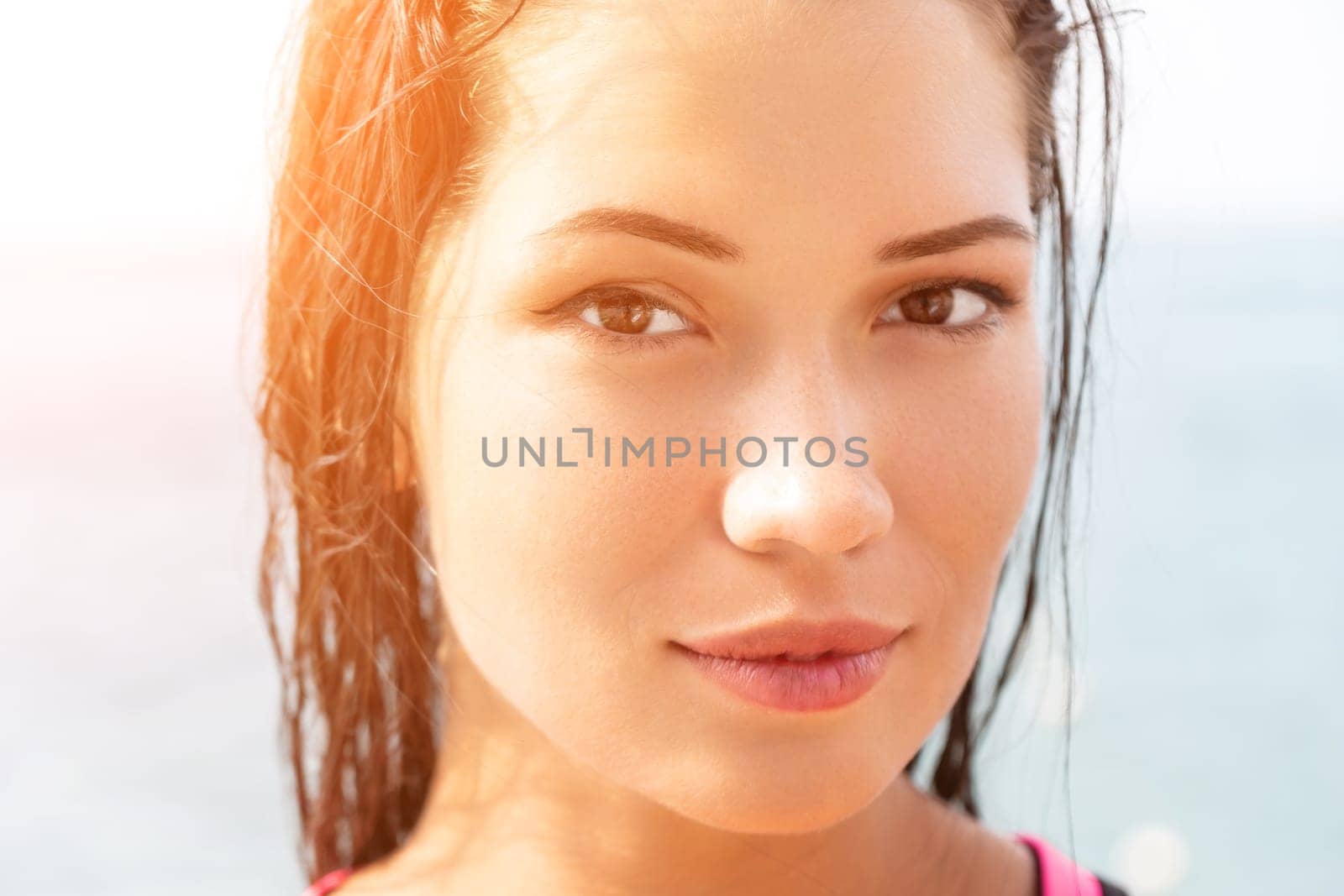 Woman sea sup. Close up portrait of beautiful young caucasian woman with black hair and freckles looking at camera and smiling. Cute woman portrait in a pink bikini posing on sup board in the sea