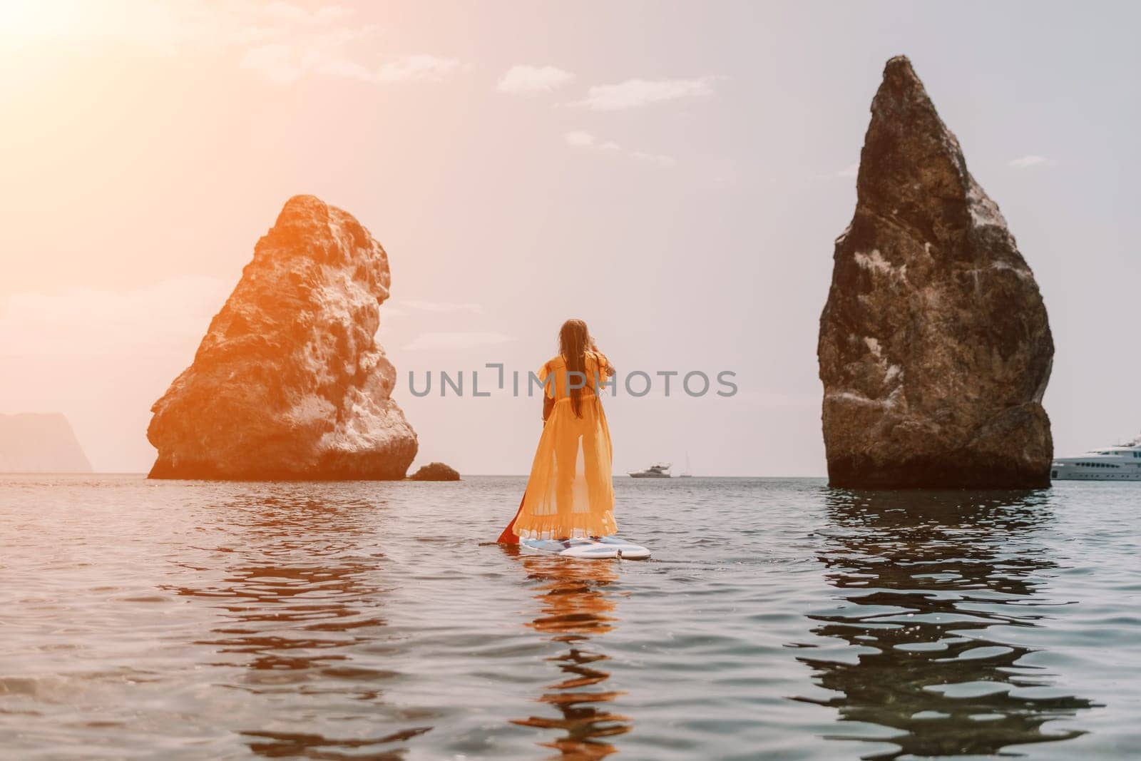 Close up shot of beautiful young caucasian woman with black hair and freckles looking at camera and smiling. Cute woman portrait in a pink bikini posing on a volcanic rock high above the sea