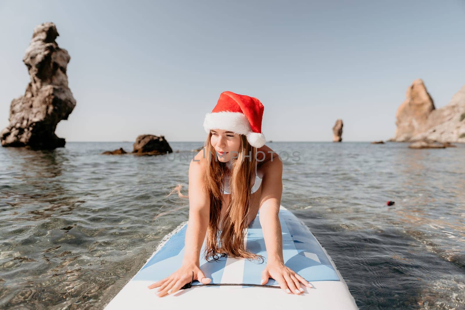 Close up shot of happy young caucasian woman looking at camera and smiling. Cute woman portrait in bikini posing on a volcanic rock high above the sea