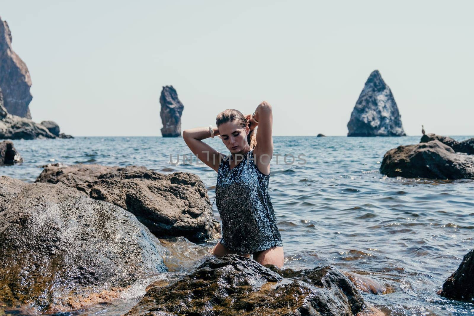 Woman summer travel sea. Happy tourist enjoy taking picture outdoors for memories. Woman traveler posing on the beach at sea surrounded by volcanic mountains, sharing travel adventure journey by panophotograph