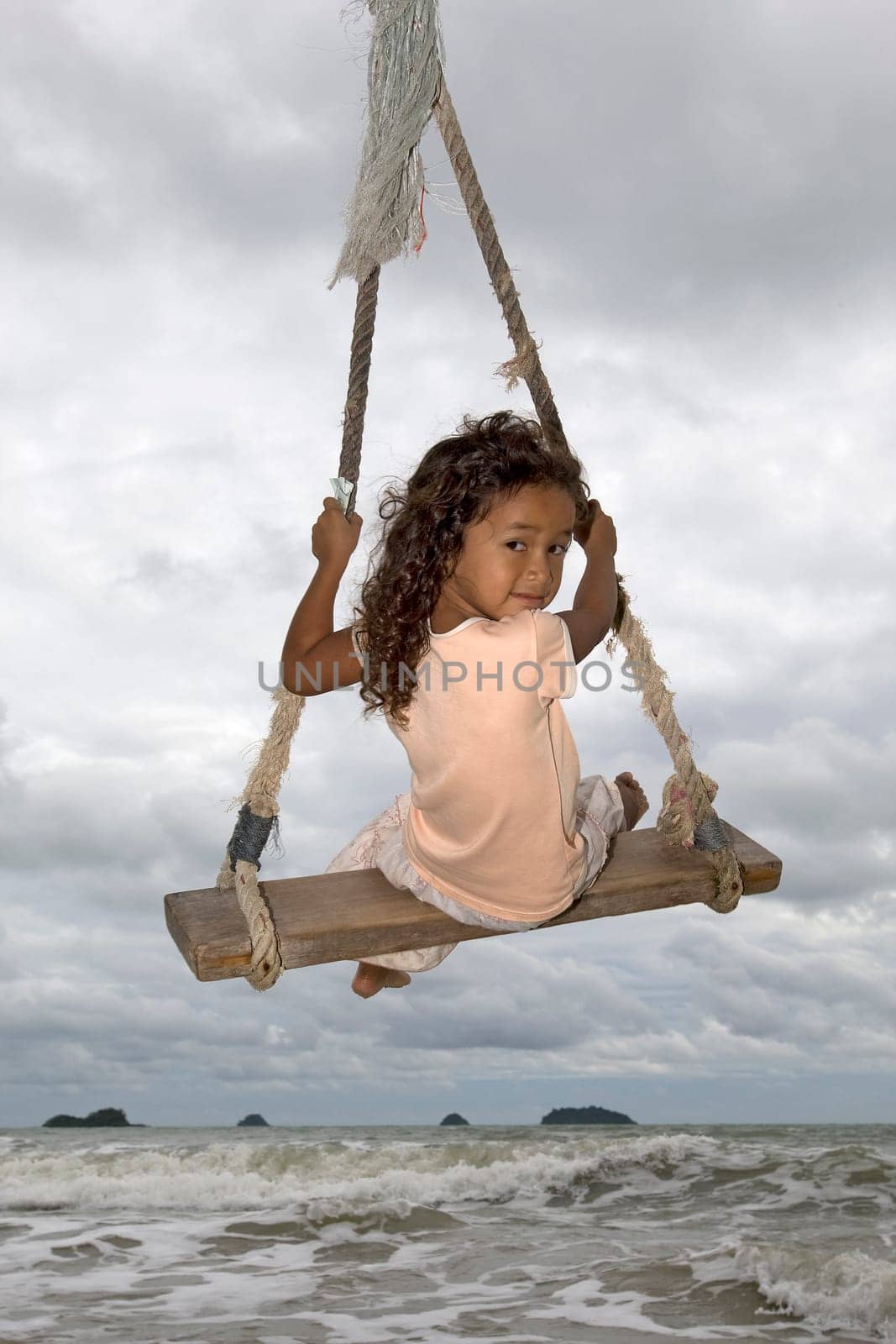 Girl on swing by the sea