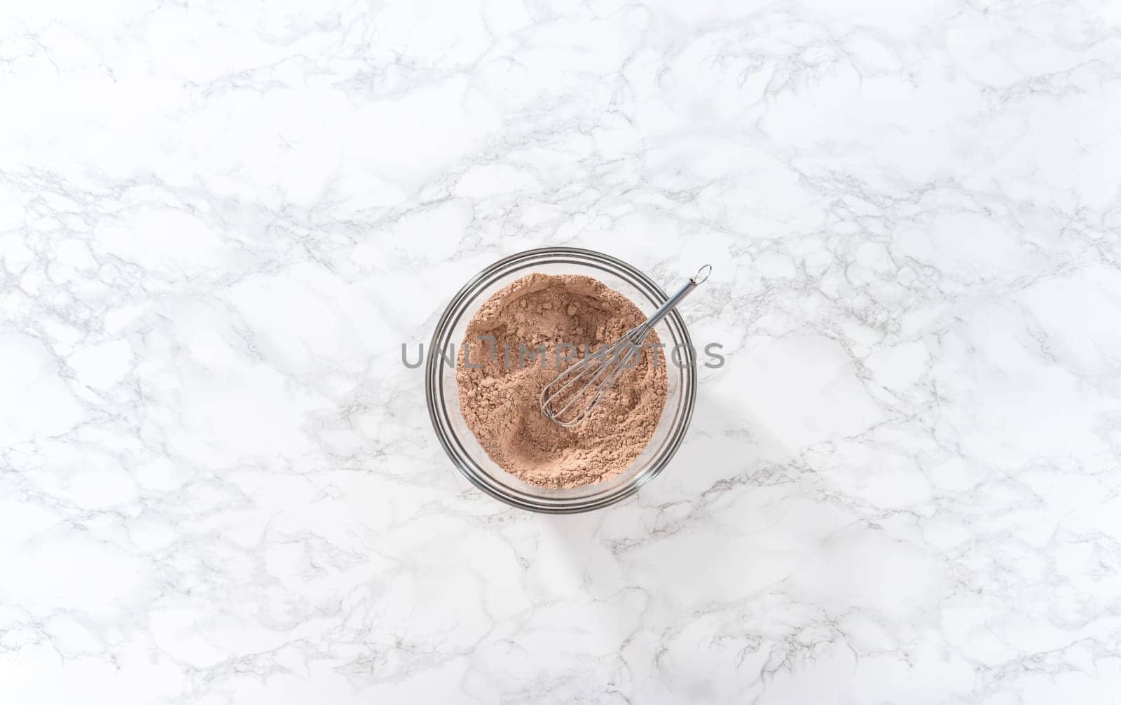 Flat lay. Mixing wet ingredients in a large glass mixing bowl to bake red velvet cupcakes with white chocolate ganache frosting.