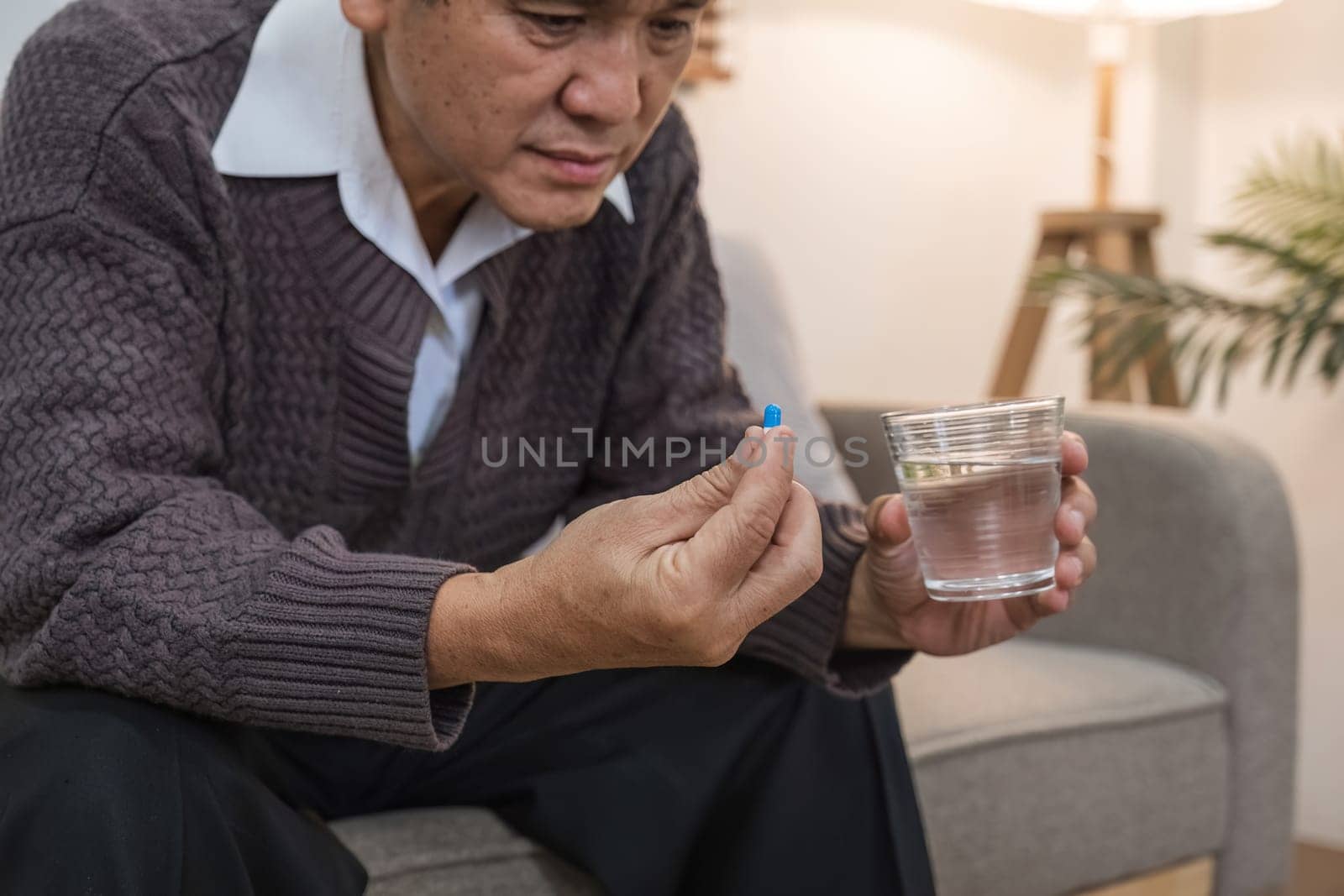 Medicine and hand of 60s man with watery medicine feeling sick Elderly person going to take painkiller from headache, painkiller, health, medicine, treatment, therapy, patient, disease concept by wichayada