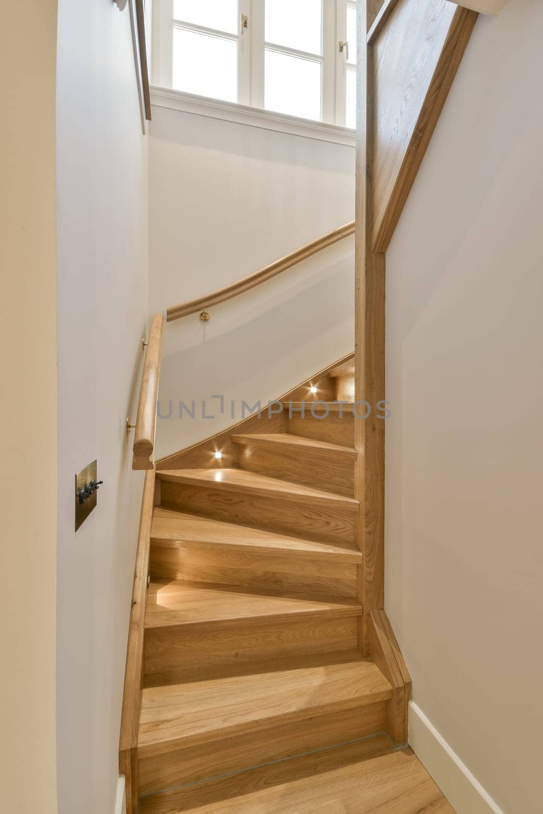 a wooden staircase leading up to the second floor in a home with white walls and light wood handrails