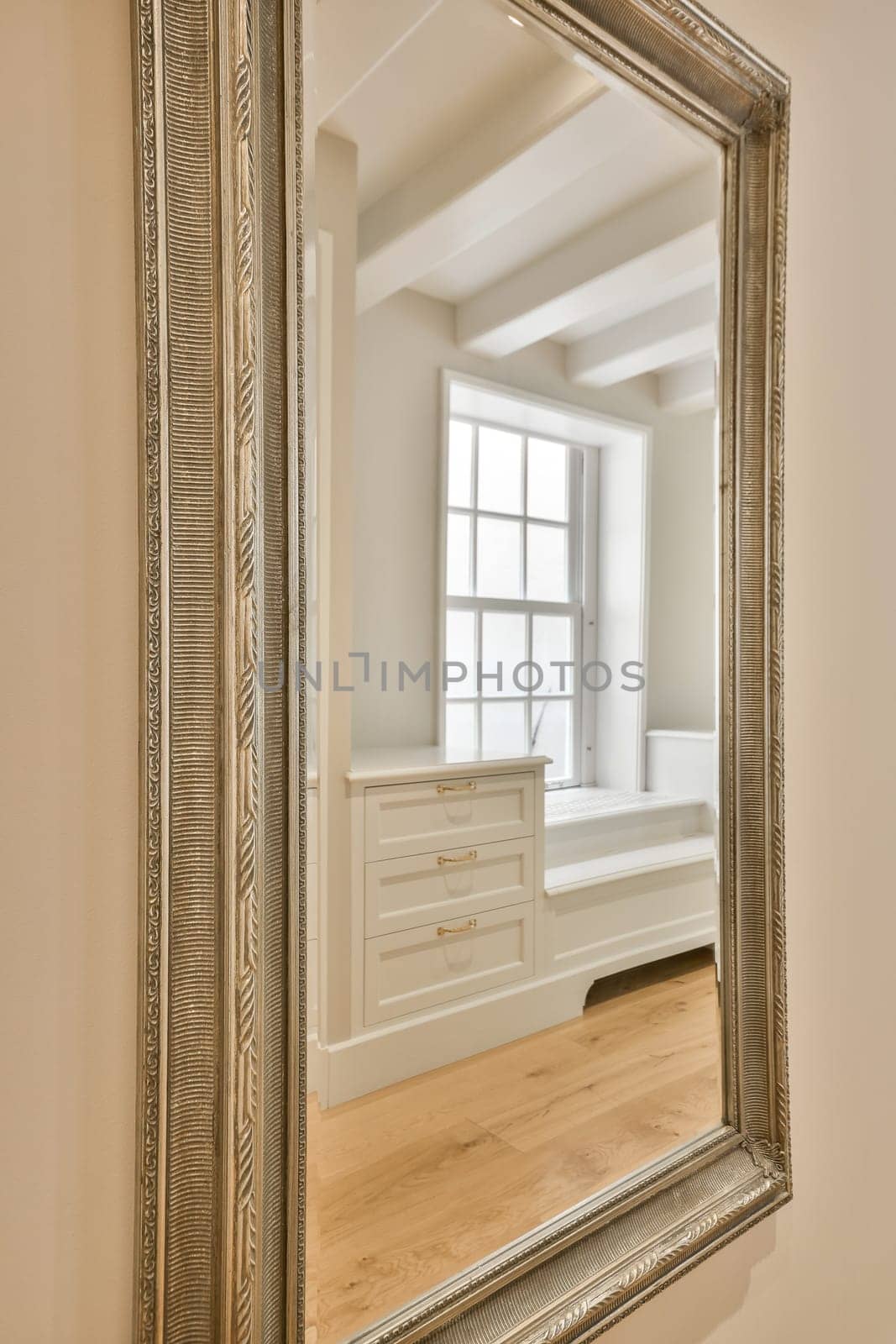 a large mirror in the corner of a room with white walls and hardwood flooring on the other side of the frame