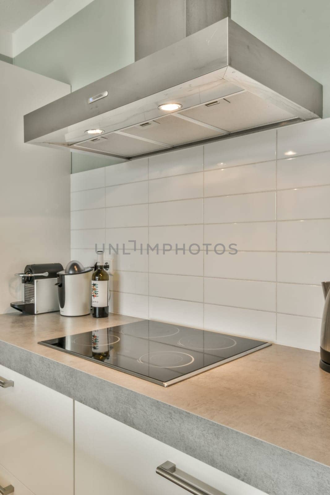 a kitchen with a stove and a white tile wall by casamedia