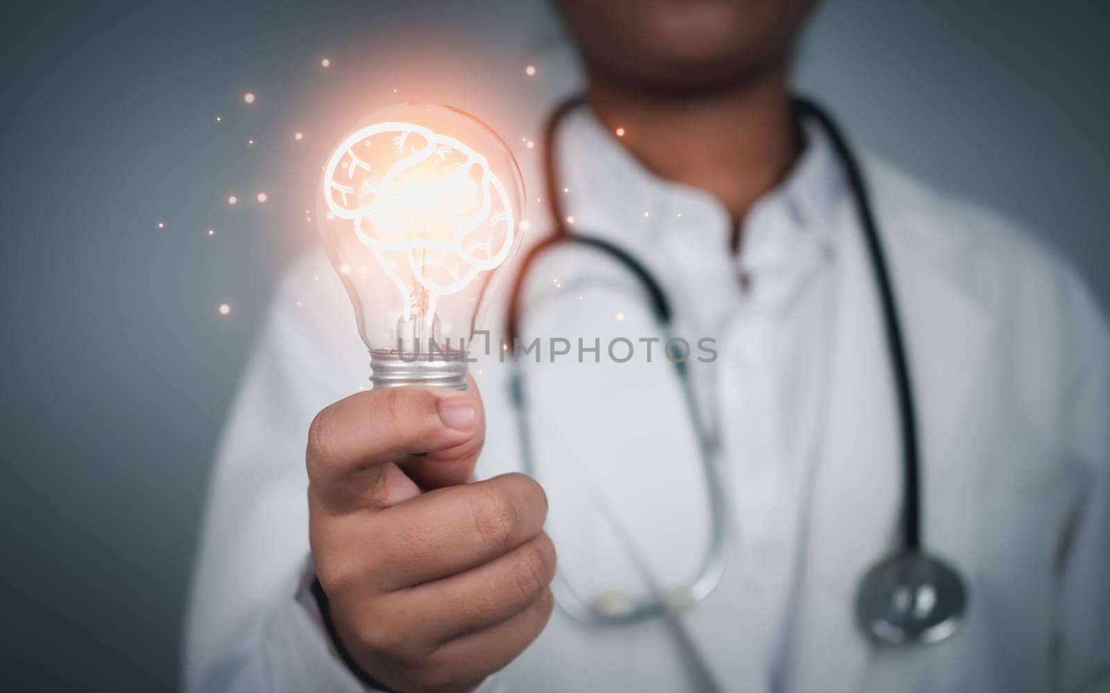 Doctor holding Light bulb with brain icon inside on grey background. Medical health care and medical services. Technology of medical service. by Unimages2527