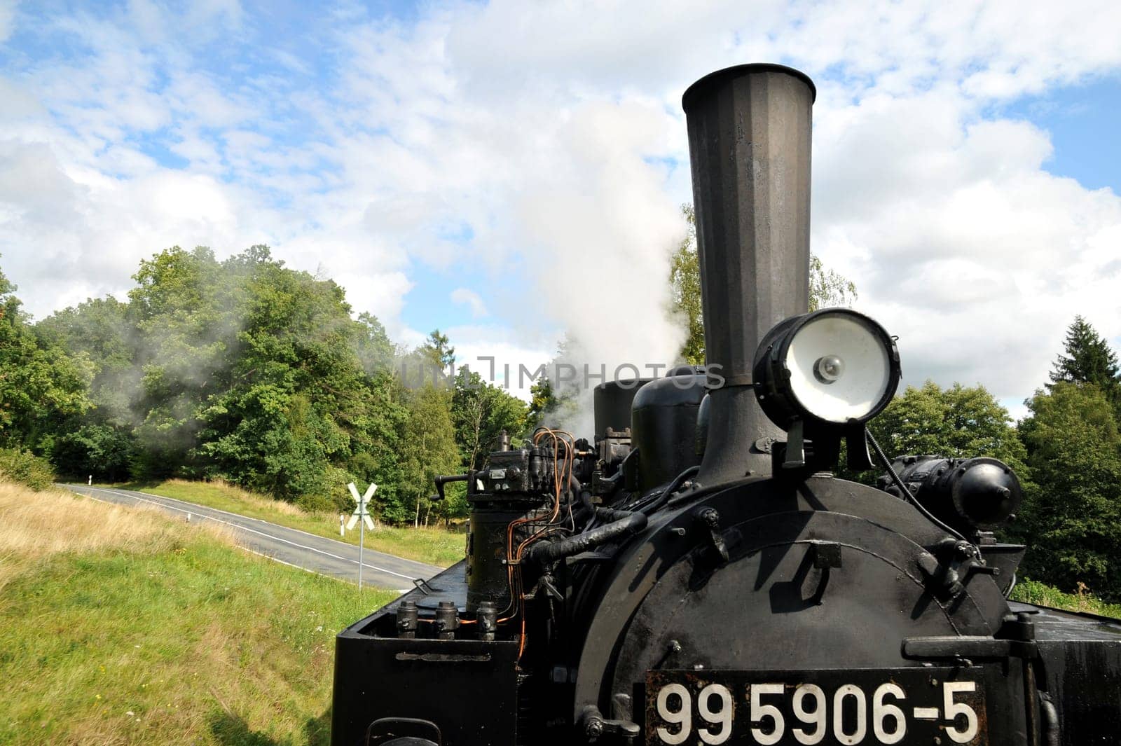 The old Mallet locomotive crosses a road in the Harz Mountains.