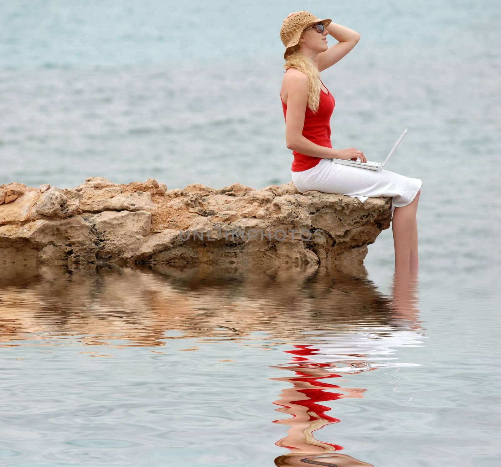 Woman using laptop by the sea
