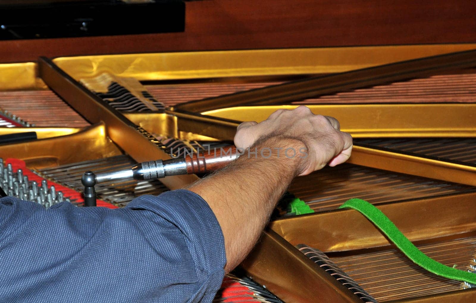 The tuning hammer is used to adjust the strings of a concert grand piano.