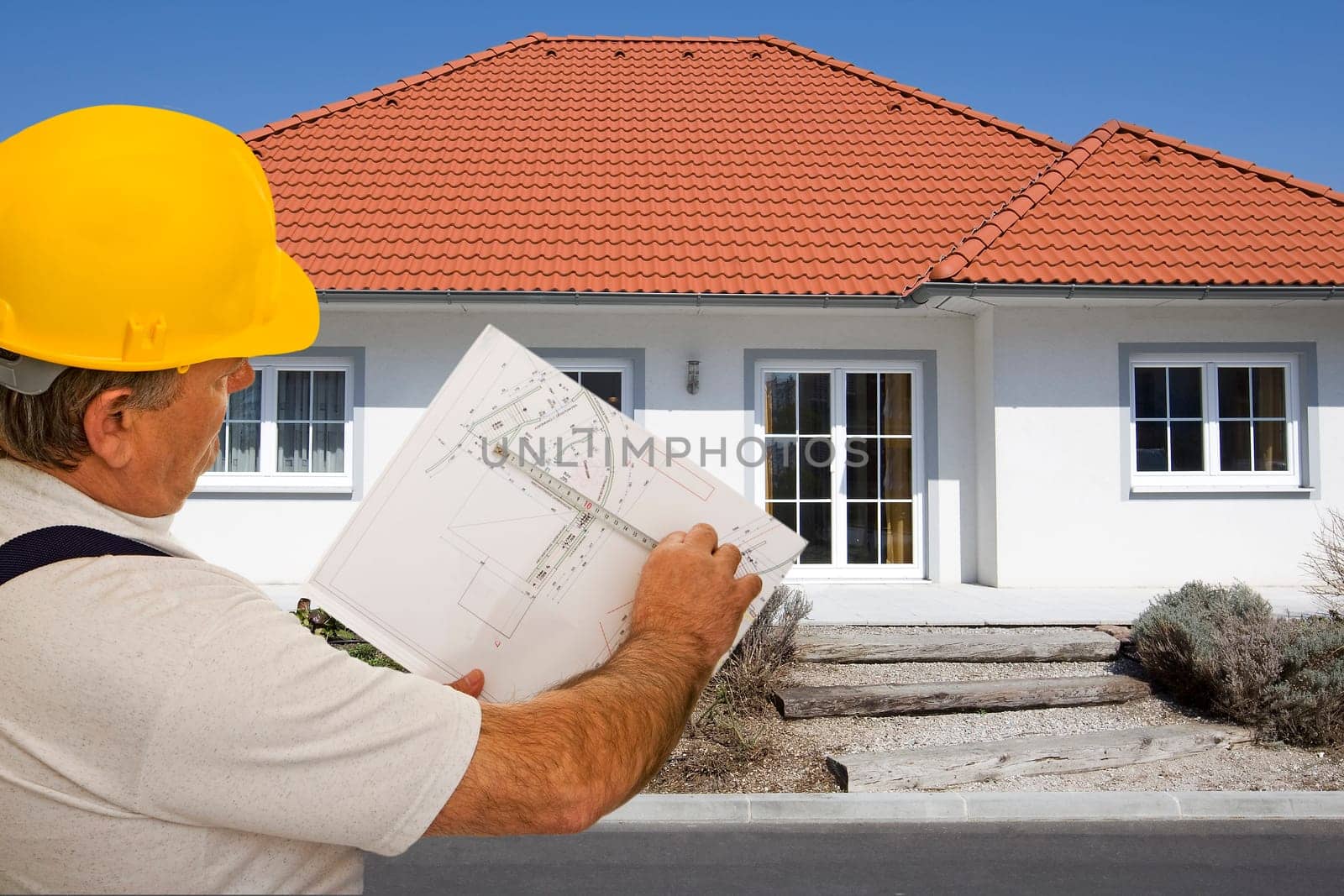 Construction worker with plan in front of house