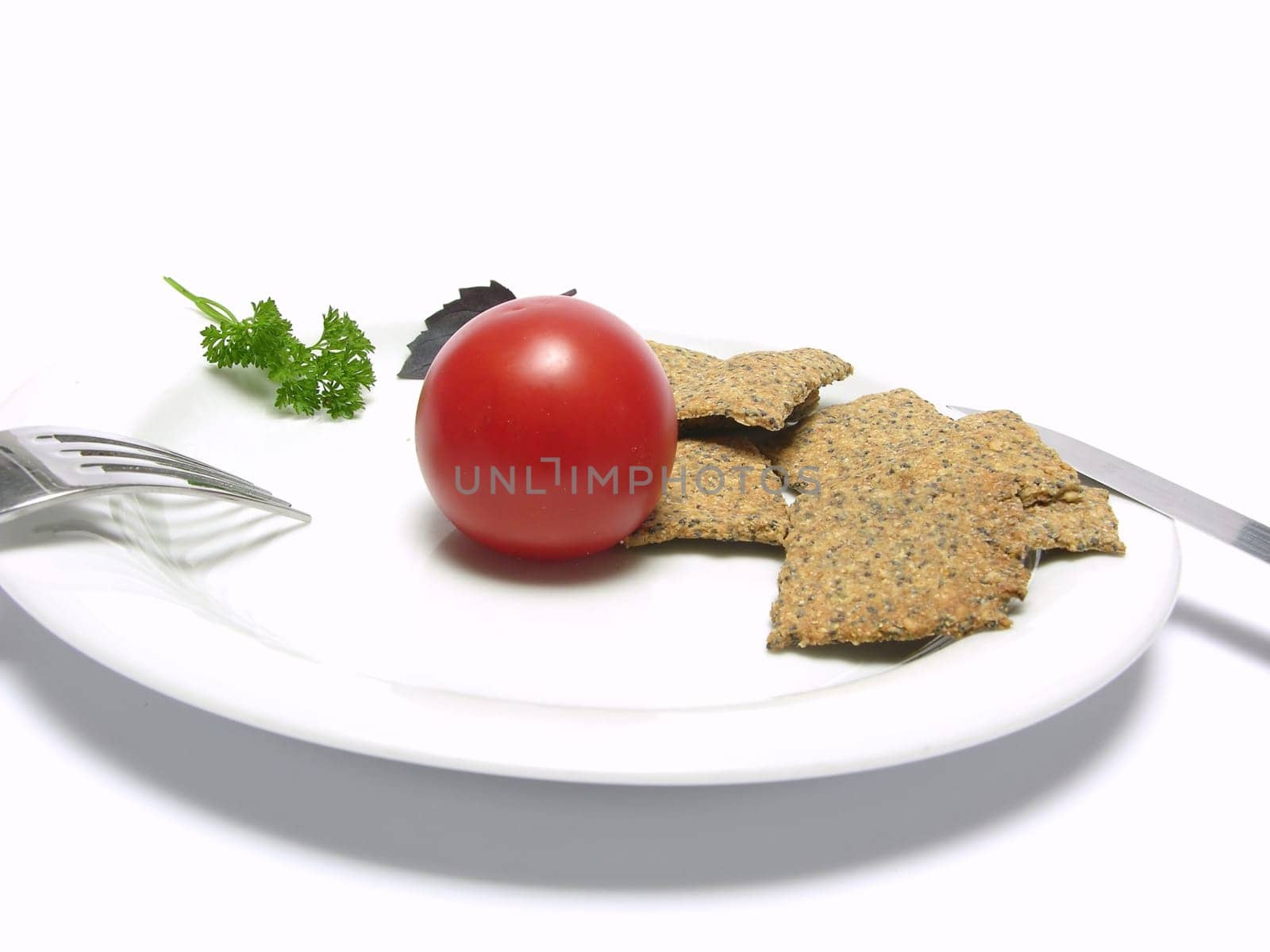 Tomato with hand make crisp bread on a white plate