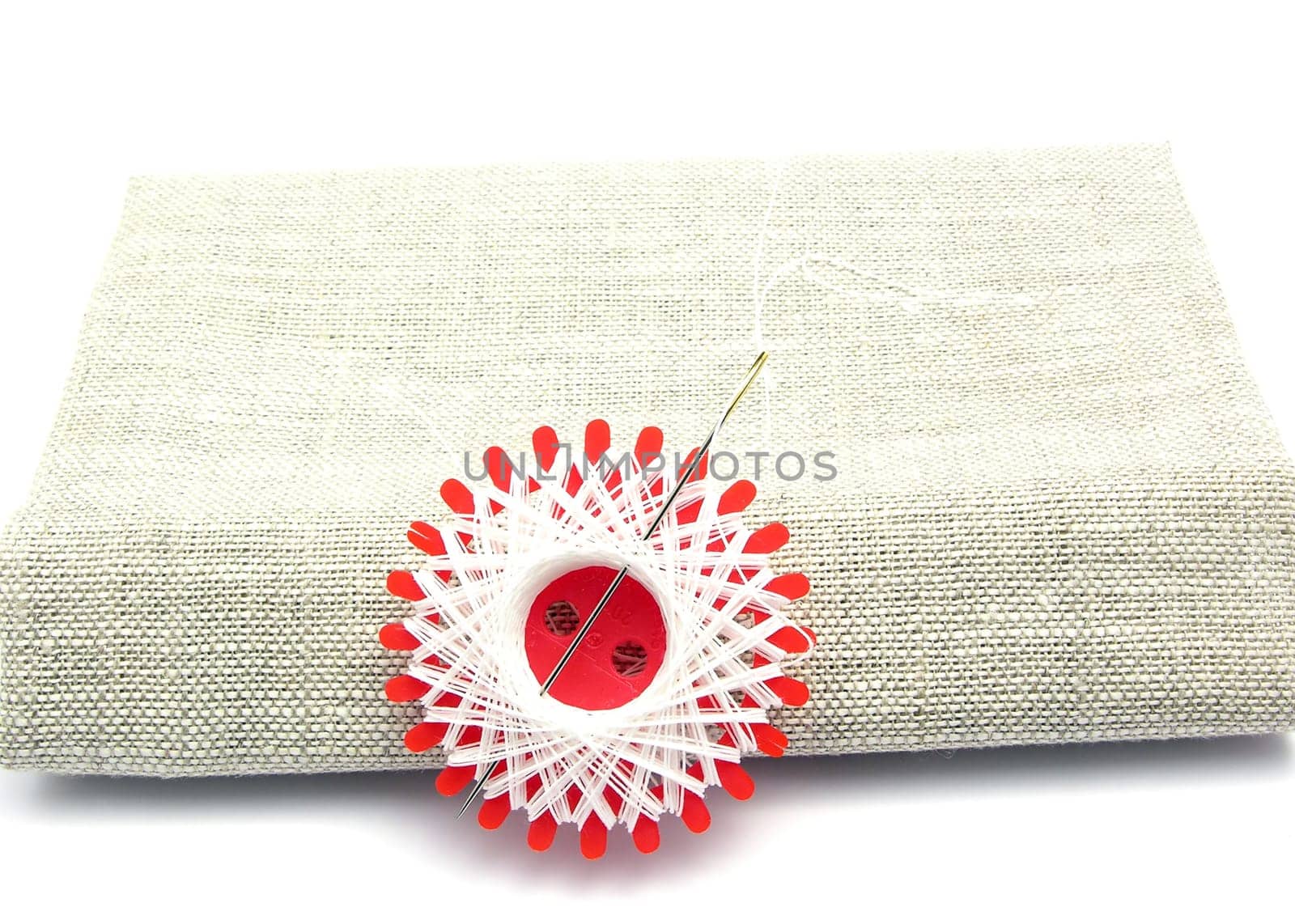 White thread with needle on linen