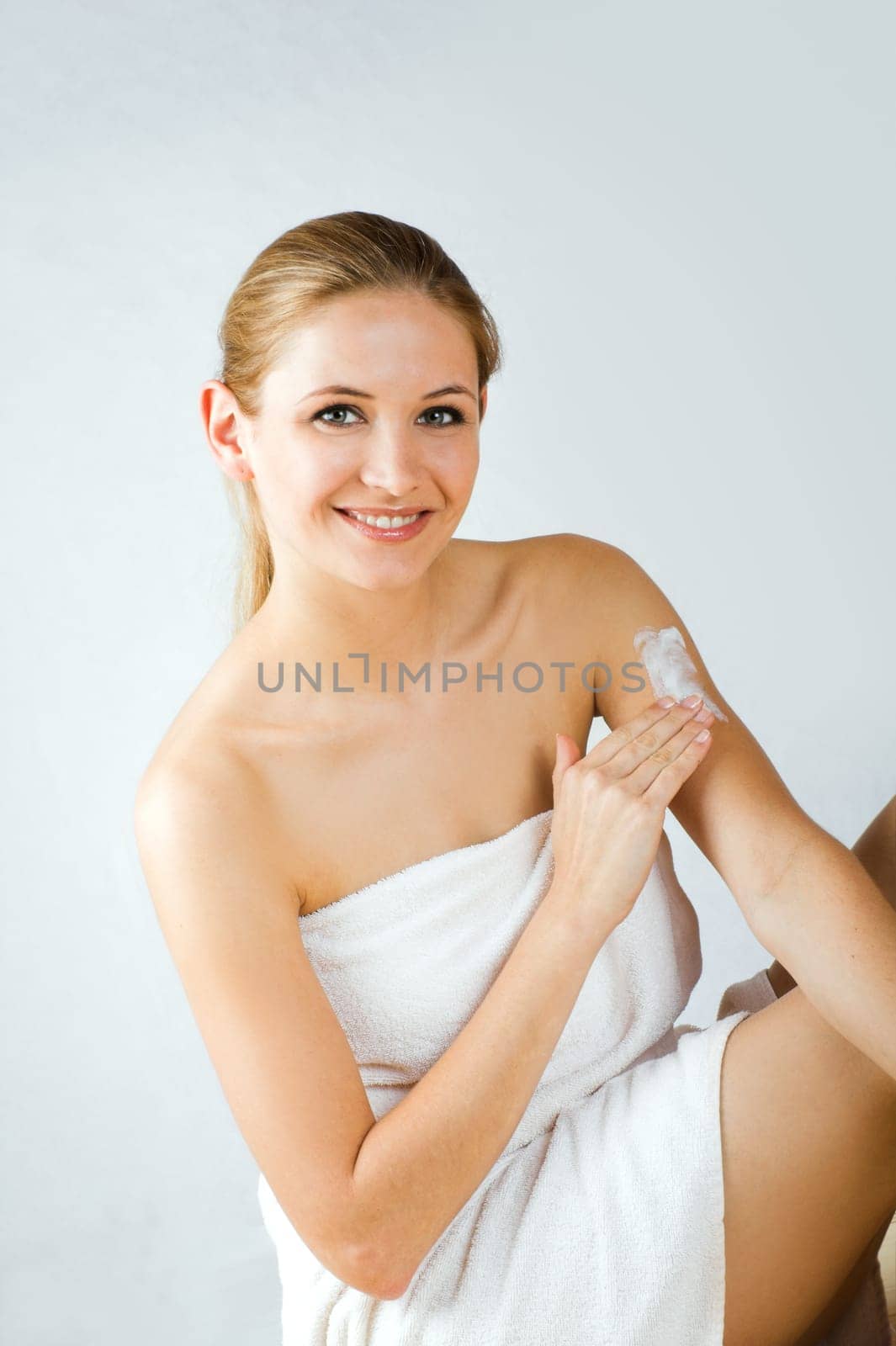 Young woman applying cream with body lotion
