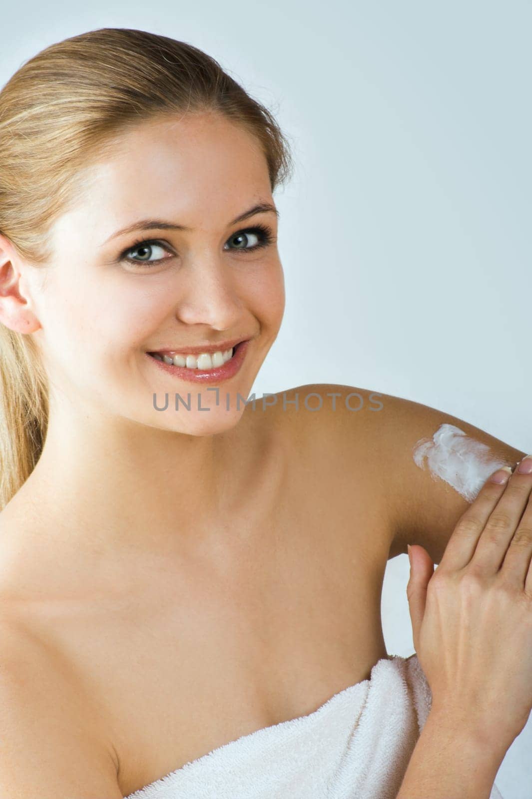 Young woman applying cream with body lotion