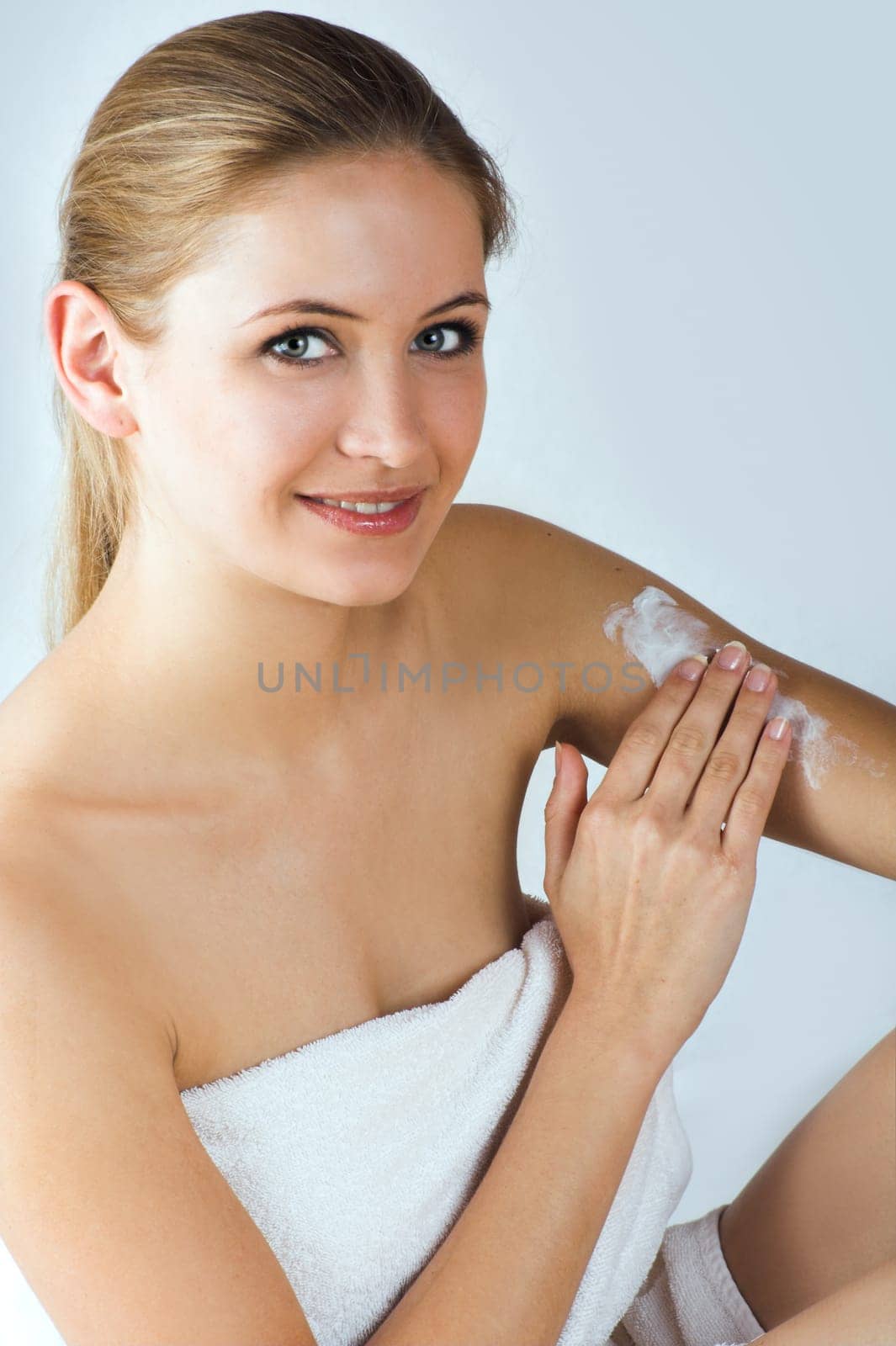 Young woman applying cream with body lotion