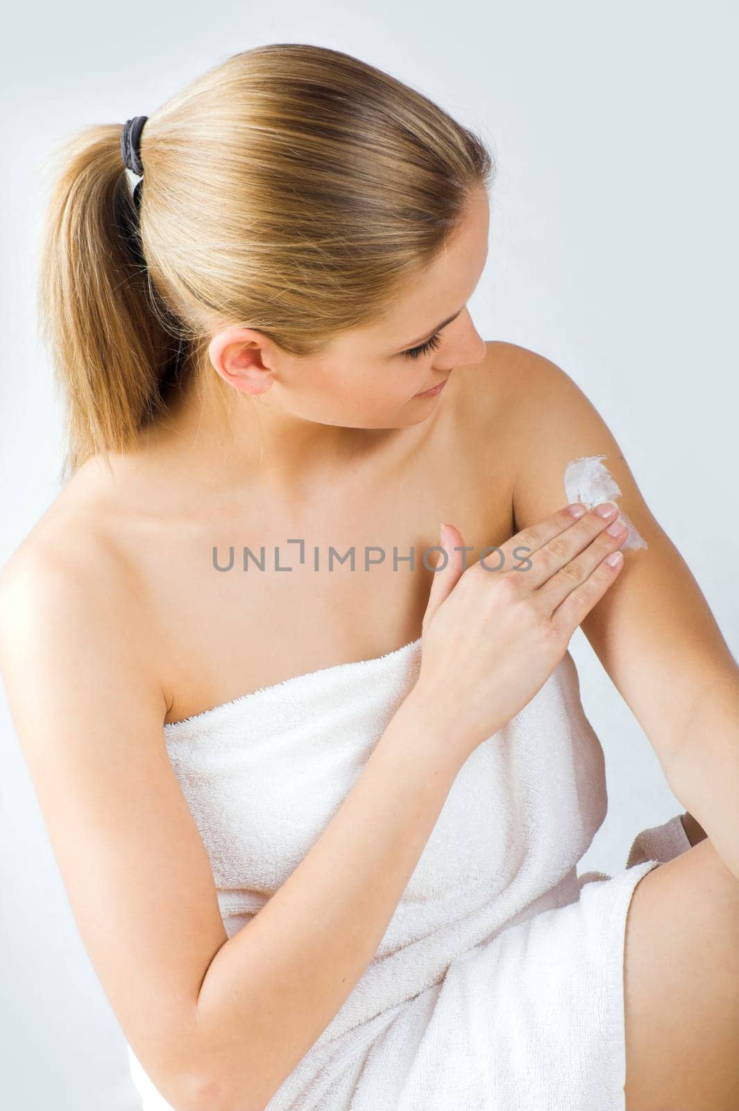 Young woman applying cream with body lotion