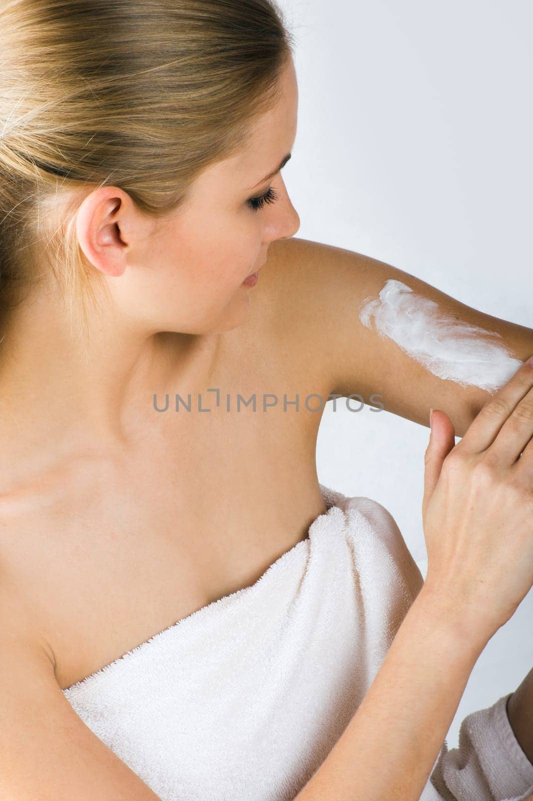 Young woman applying cream with body lotion
