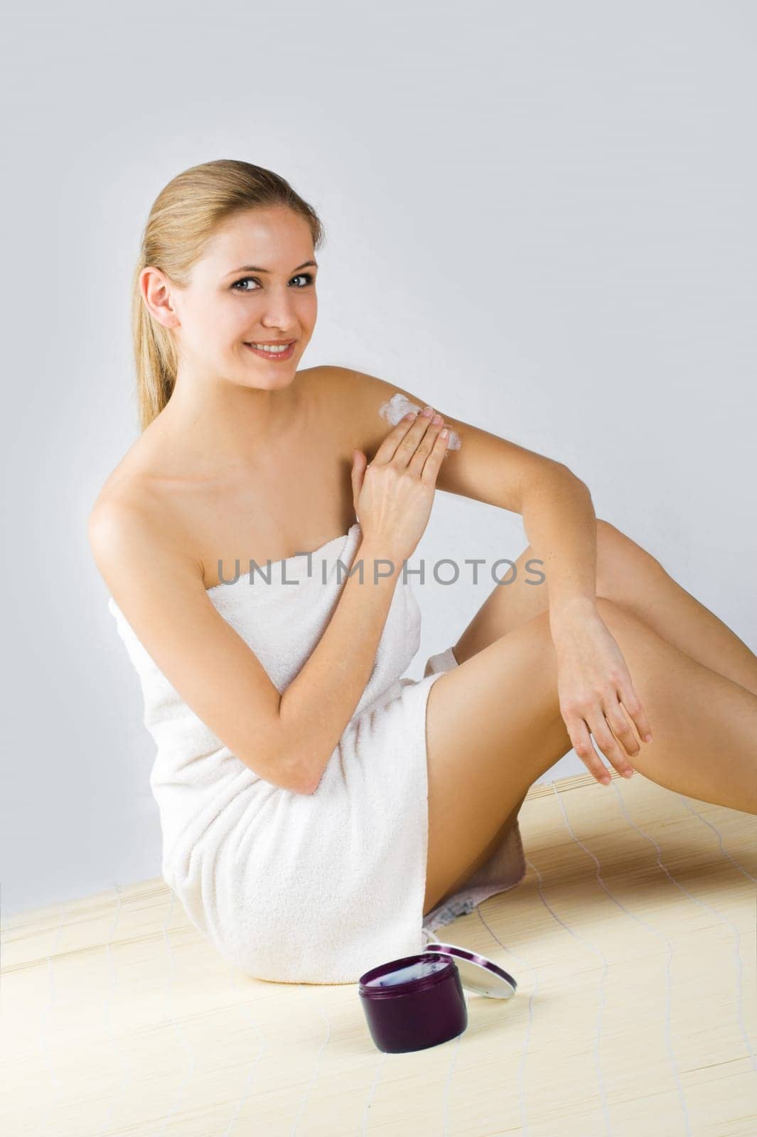 Young woman applying cream with body lotion