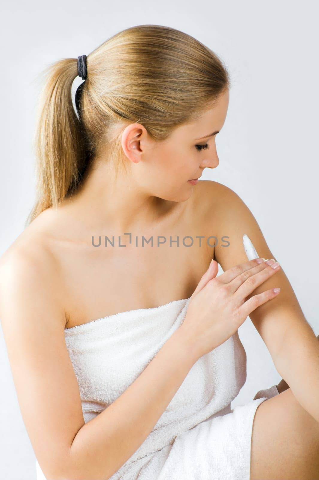 Young woman applying cream with body lotion