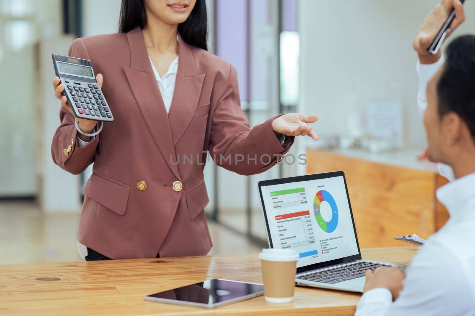 Businesswoman advise colleague about finance report on calculator in office.